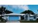 Charming one-story home with white exterior, blue trim, well-manicured lawn, and blue garage door at 1039 Greenturf Rd, Spring Hill, FL 34608