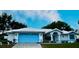 Charming one-story home with white exterior, blue trim, well-manicured lawn, and blue garage door at 1039 Greenturf Rd, Spring Hill, FL 34608