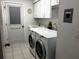 Well-lit laundry room with washer, dryer, utility sink, and built-in cabinets for storage at 1039 Greenturf Rd, Spring Hill, FL 34608