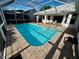 A refreshing screened-in pool with a brick paved patio and a sunny seating area at 1039 Greenturf Rd, Spring Hill, FL 34608