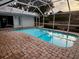 Outdoor pool with brick paver deck, screen enclosure and view of yard with a small pond at 1039 Greenturf Rd, Spring Hill, FL 34608