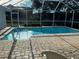 A refreshing screened-in pool with a brick paved patio, overlooking a fenced-in yard at 1039 Greenturf Rd, Spring Hill, FL 34608