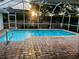 A refreshing screened-in pool with a brick paved patio, with sunset view over backyard at 1039 Greenturf Rd, Spring Hill, FL 34608