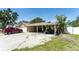 Charming single-story home showcasing a driveway with a vehicle, a carport, and a partially shaded front yard at 11996 117Th St, Seminole, FL 33778