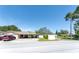 Charming single-story home showcasing a driveway with two vehicles, a carport, and a partially shaded front yard at 11996 117Th St, Seminole, FL 33778