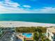 Aerial view of the resort, ocean, white sand beach and a pool with many lounge chairs at 12000 Gulf Blvd # 506N, Treasure Island, FL 33706