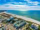 Aerial view shows a pristine beach, turquoise ocean, and coastal buildings in a sunny locale at 12000 Gulf Blvd # 506N, Treasure Island, FL 33706