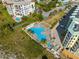 Aerial view of a uniquely shaped pool, sun deck, and lounge chairs, conveniently located next to condo building at 12000 Gulf Blvd # 506N, Treasure Island, FL 33706