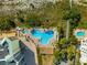 Aerial view of a uniquely shaped pool with a sun deck, lounge chairs, palm trees, and convenient beach access at 12000 Gulf Blvd # 506N, Treasure Island, FL 33706