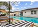 Backyard pool area with lounge chairs, patio umbrellas, lush landscaping, and an adjacent building at 1242 Whisper Dr, Largo, FL 33770