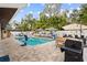 Backyard pool area with a stone patio, lounge chairs, patio umbrellas, and landscaping at 1242 Whisper Dr, Largo, FL 33770
