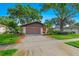 Charming single-Gathering home boasts a manicured lawn, mature trees, and convenient two-car garage at 1242 Whisper Dr, Largo, FL 33770