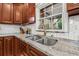 Detailed view of the kitchen sink, featuring granite countertop and subway tile backsplash at 1242 Whisper Dr, Largo, FL 33770