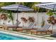 Lounge area by the pool, equipped with striped lounge chairs and decorative umbrellas at 1242 Whisper Dr, Largo, FL 33770