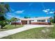Inviting single-story home featuring a brick and stucco exterior, well-manicured lawn, and a curved driveway at 13883 Jamaica Dr, Seminole, FL 33776