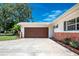 Spacious two-car garage with a stained wood door, complemented by a well-maintained driveway and landscaping at 13883 Jamaica Dr, Seminole, FL 33776