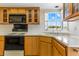 Cozy kitchen with wooden cabinets, black appliances, and a bright window view at 13883 Jamaica Dr, Seminole, FL 33776