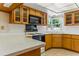 Kitchen featuring white countertops, a window view, and wood cabinets at 13883 Jamaica Dr, Seminole, FL 33776