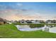 Scenic backyard view at dusk featuring a tranquil pond and lush green lawn at 1821 Hawks View Dr, Ruskin, FL 33570