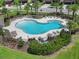 Aerial view of a community pool featuring lounge chairs, palm trees, and lush landscaping for a relaxing outdoor experience at 1821 Hawks View Dr, Ruskin, FL 33570
