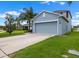 Charming two-story blue home featuring a two-car garage, a large driveway, and lush green lawn at 1821 Hawks View Dr, Ruskin, FL 33570