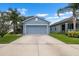 Charming blue two-story home featuring a large driveway, a two-car garage, and lush tropical landscaping at 1821 Hawks View Dr, Ruskin, FL 33570