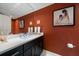 Stylish powder room with a large mirror and dark vanity against rust-colored walls at 2 Seaside Ln # 203, Belleair, FL 33756