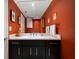 Elegant powder room with a white countertop and dark vanity, complemented by striking rust-colored walls at 2 Seaside Ln # 203, Belleair, FL 33756