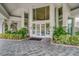 Grand building entrance with large glass doors, tile walkway, and mature landscaping at 2 Seaside Ln # 203, Belleair, FL 33756