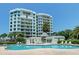 Upscale condo building with a stunning swimming pool, lounge chairs, and lush landscaping at 2 Seaside Ln # 203, Belleair, FL 33756