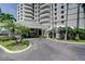 Luxury condo building entrance with lush landscaping and circular driveway at 2 Seaside Ln # 203, Belleair, FL 33756