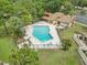 Aerial view of the community pool and clubhouse, surrounded by lush landscaping and lounge chairs at 2078 Sunset Point Rd # 83, Clearwater, FL 33765