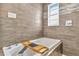 Modern bathtub with wood caddy, stylish faucet, and gray stone-look tiled walls at 2205 N Riverside Dr, Tampa, FL 33602