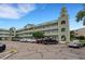 Low angle shows the building's facade, three stories, arched entryway, decorated railings, and parking lot in front at 2256 Philippine Dr # 24, Clearwater, FL 33763
