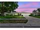 Charming single-story home featuring a well-manicured lawn, mature trees, and a two-car garage under a pastel sky at 2418 Cardwell Way, Sarasota, FL 34231