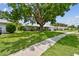The front yard showcases a mature tree providing shade over the house, with a lush lawn extending to the sidewalk at 2418 Cardwell Way, Sarasota, FL 34231