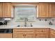 Classic kitchen featuring a double sink, window view, and light wood cabinetry at 2418 Cardwell Way, Sarasota, FL 34231