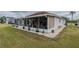 View of the home from the backyard, highlighting the screened lanai and well-maintained lawn at 2457 E Del Webb Blvd, Sun City Center, FL 33573