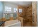 Well-appointed bathroom featuring a separate tub and shower with travertine tile and updated fixtures at 2457 E Del Webb Blvd, Sun City Center, FL 33573