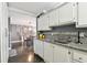 Galley kitchen featuring granite countertops, white cabinetry, mosaic tile backsplash and stainless steel sink at 255 Dolphin Pt # 207, Clearwater Beach, FL 33767