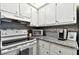 Galley kitchen featuring granite countertops, white cabinetry, mosaic tile backsplash and stainless steel sink at 255 Dolphin Pt # 207, Clearwater Beach, FL 33767