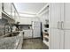 Galley kitchen featuring granite countertops, white cabinetry, mosaic tile backsplash and stainless steel sink at 255 Dolphin Pt # 207, Clearwater Beach, FL 33767