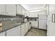Galley kitchen featuring granite countertops, white cabinetry, mosaic tile backsplash and stainless steel sink at 255 Dolphin Pt # 207, Clearwater Beach, FL 33767