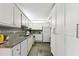 Galley kitchen featuring granite countertops, white cabinetry, mosaic tile backsplash and stainless steel sink at 255 Dolphin Pt # 207, Clearwater Beach, FL 33767