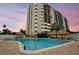 Community pool area with palm trees, tiki hut umbrellas, and lounge chairs at 255 Dolphin Pt # 207, Clearwater Beach, FL 33767