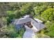 Aerial view of a beautiful, landscaped property with a red brick house, a screened in pool, and mature trees at 302 Eastleigh Dr, Belleair, FL 33756