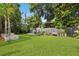 Manicured backyard with lush lawn, mature trees, and charming garden beds at 302 Eastleigh Dr, Belleair, FL 33756