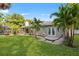 Relaxing backyard featuring a manicured lawn, patio, and mature palm trees for shade at 302 Eastleigh Dr, Belleair, FL 33756