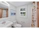 Bathroom featuring a toilet, shower, vanity sink and a window with white shutters at 302 Eastleigh Dr, Belleair, FL 33756