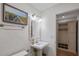 Elegant half bathroom with a white pedestal sink, decorative mirror, and an artful beach scene at 302 Eastleigh Dr, Belleair, FL 33756